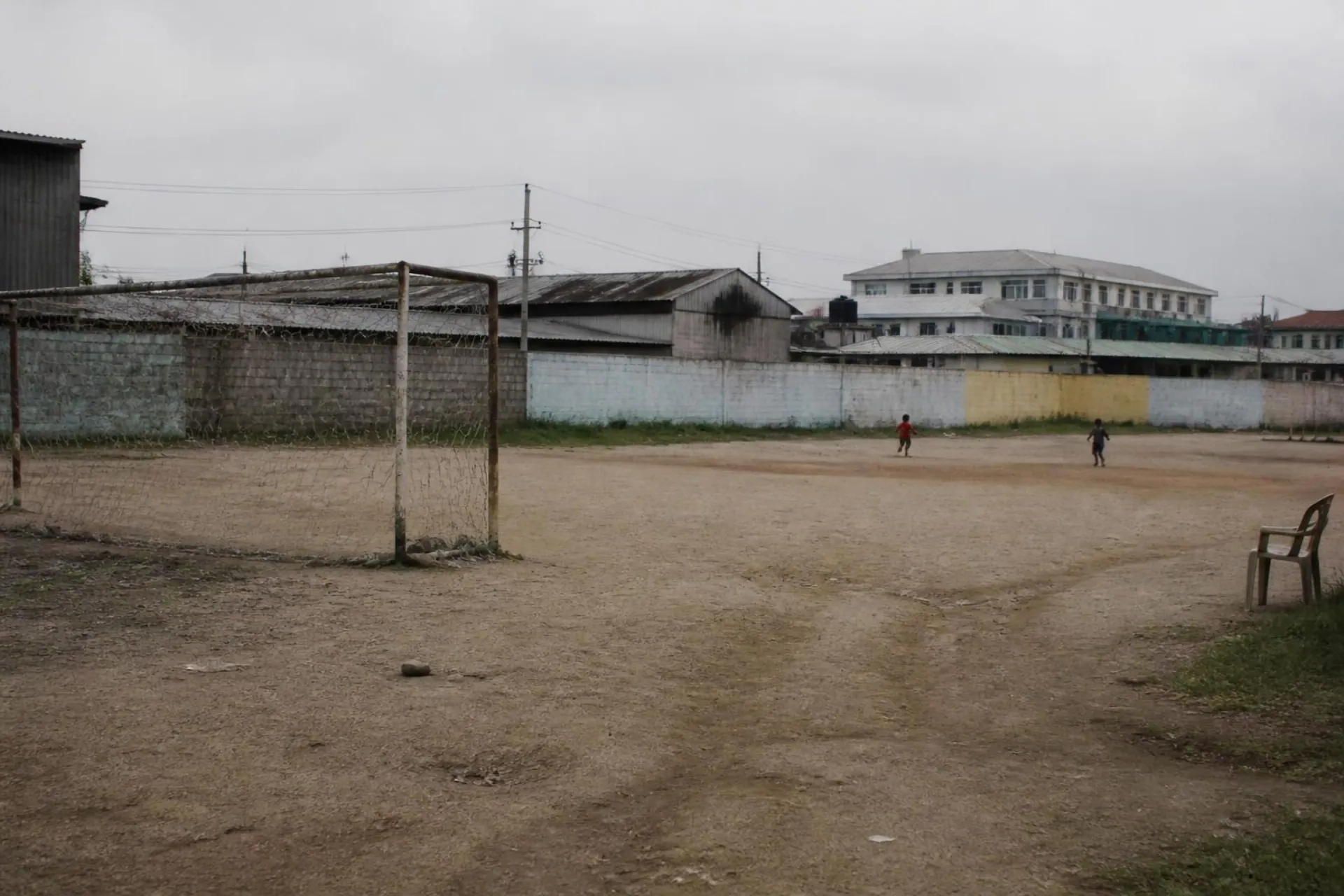 An empty dirt pitch at dusk under acacia trees